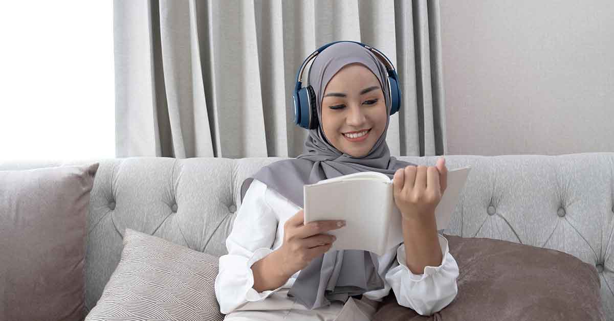 Seorang gadis sedang membaca buku sambil mendengarkan musik